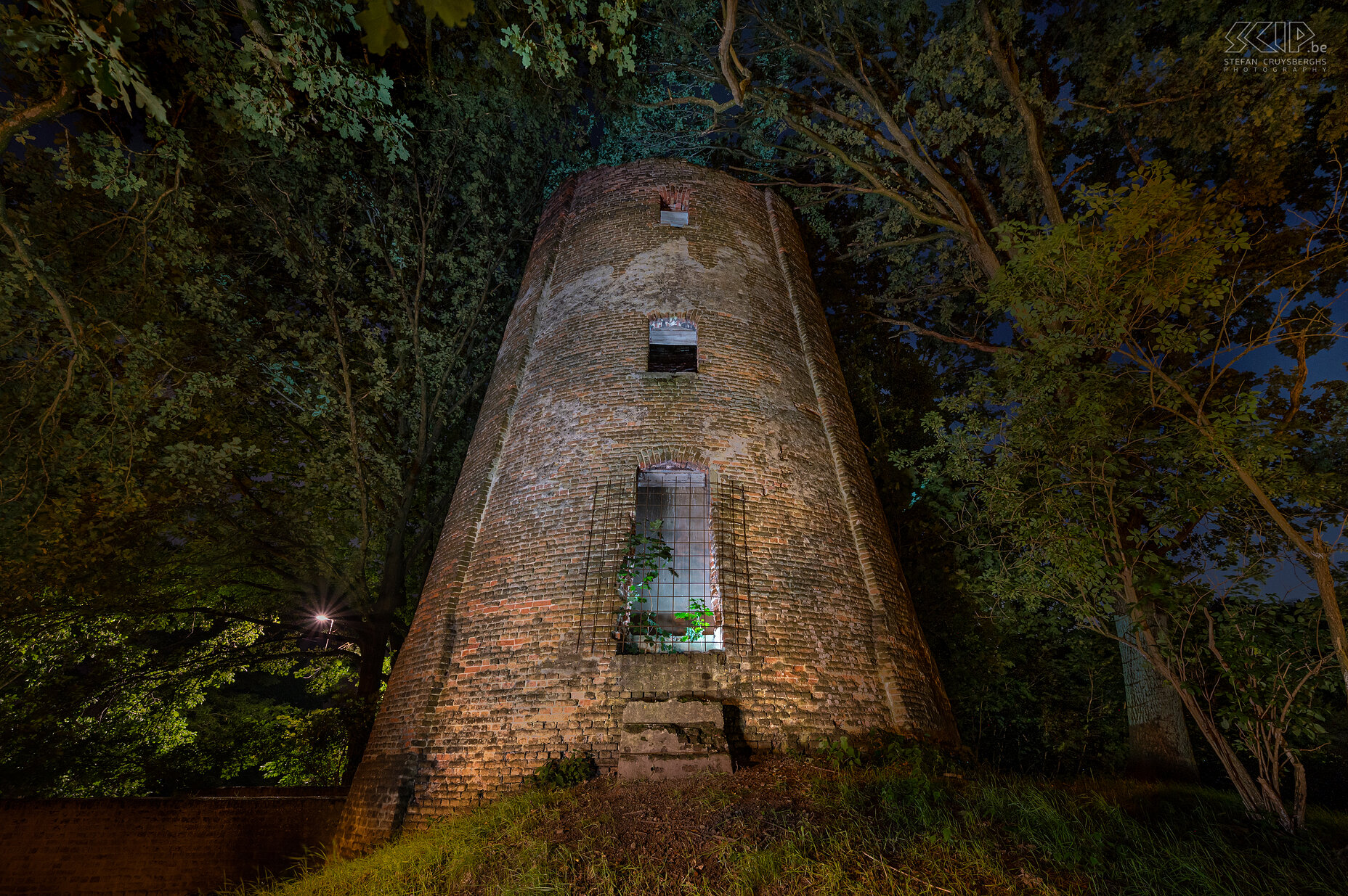 Hageland by night - Engsbergse Molen in Tessenderlo De Engsbergse Molen in Tessenderlo was een graanmolen die werd gebouwd in 1826. Sinds 1934 is de molen niet meer in gebruik en ondertussen is het een ruïne die in een woonwijk tussen de bomen staat. Fotogeniek is de molen totaal niet meer en toch heb ik geprobeerd om er ’s avonds met een paar flitsers en LED lampen een paar sfeervolle beelden van te maken.  Stefan Cruysberghs